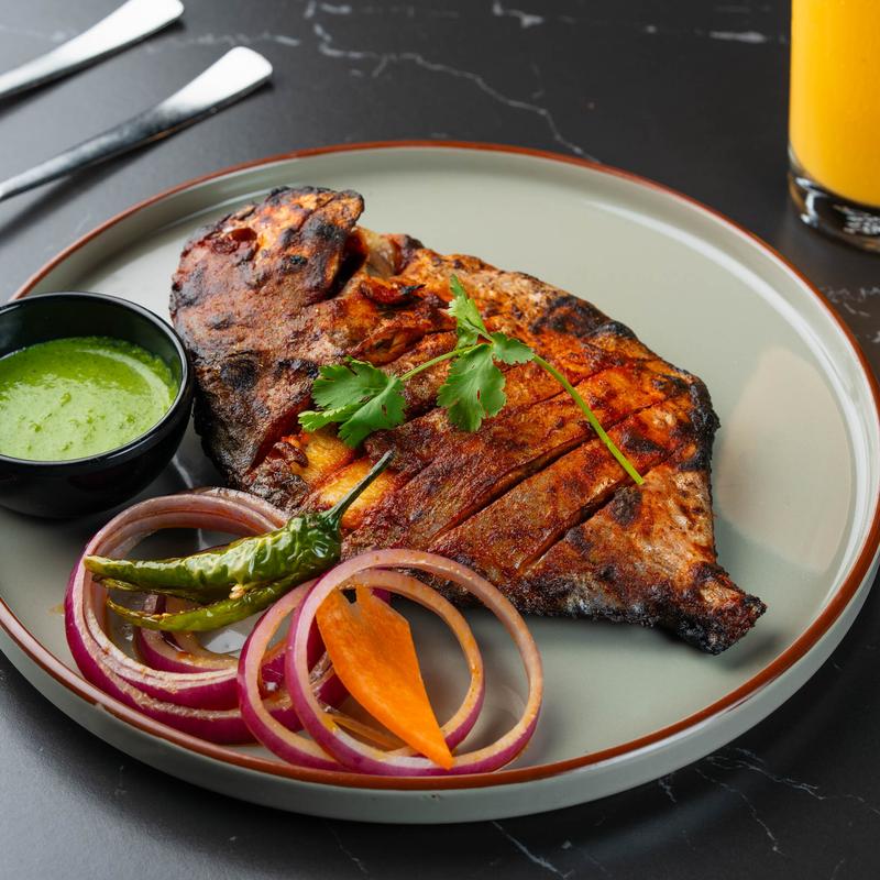 Tandoori whole fish with veggies and dipping sauce.