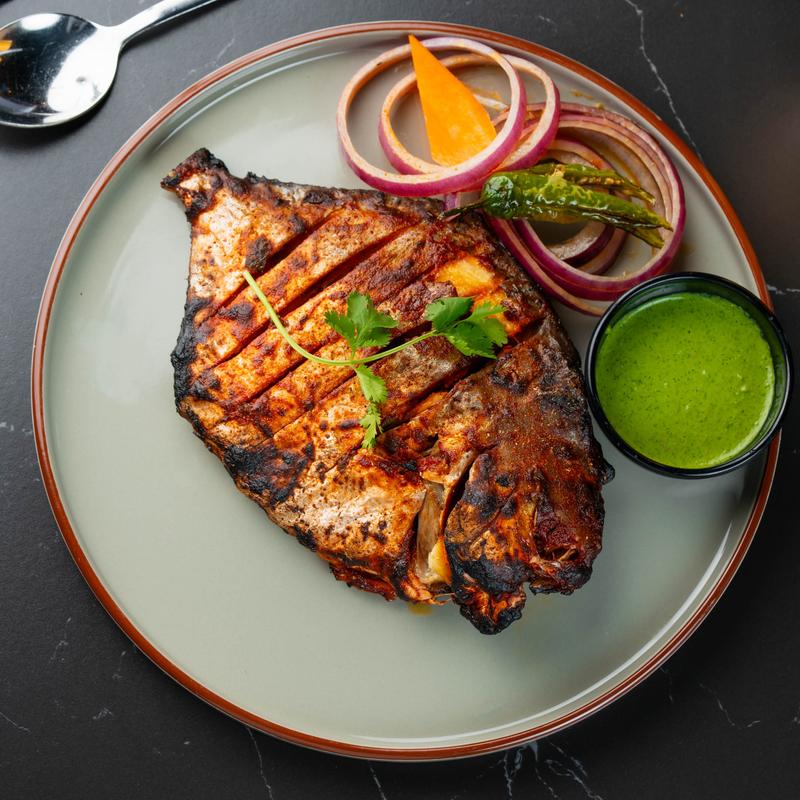Tandoori whole fish with veggies and dip.